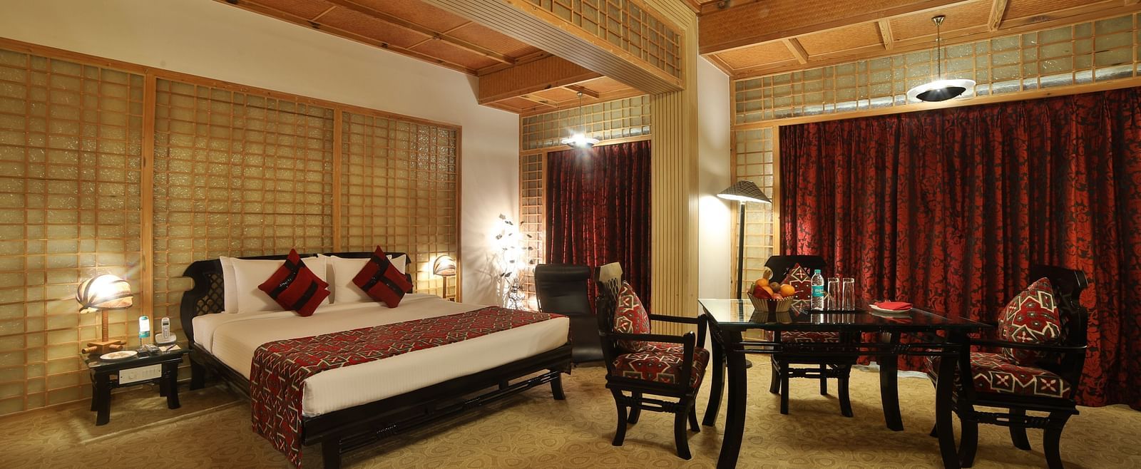 A sophisticated hotel room combining traditional design with modern amenities, featuring a large bed and seating area A grand hotel suite with an opulent red and white decor, large bed, and seating area, reflecting a traditional style at Sitara Luxury Hote