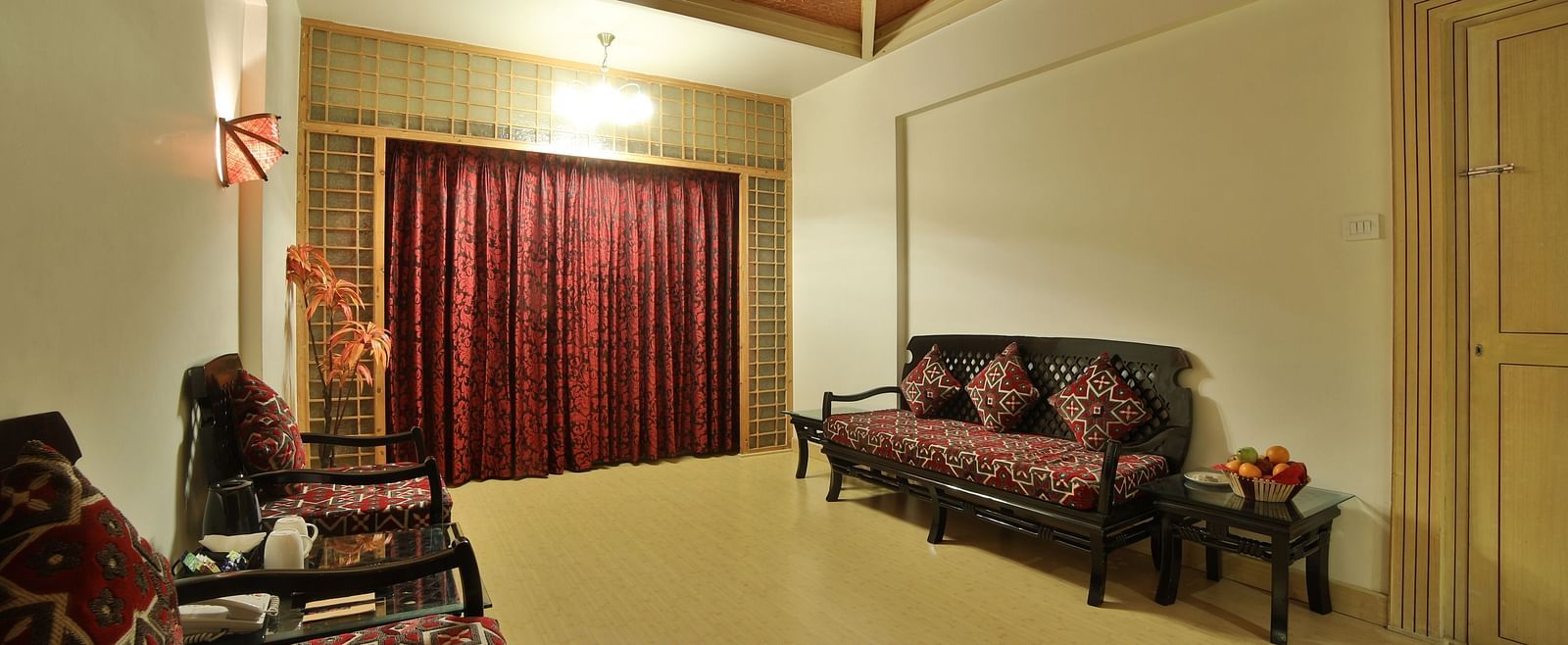 A spacious living area in a hotel suite with plush sofas, patterned upholstery, and a serene ambiance A grand hotel suite with an opulent red and white decor, large bed, and seating area, reflecting a traditional style at Sitara Luxury Hotel in Hyderabad n