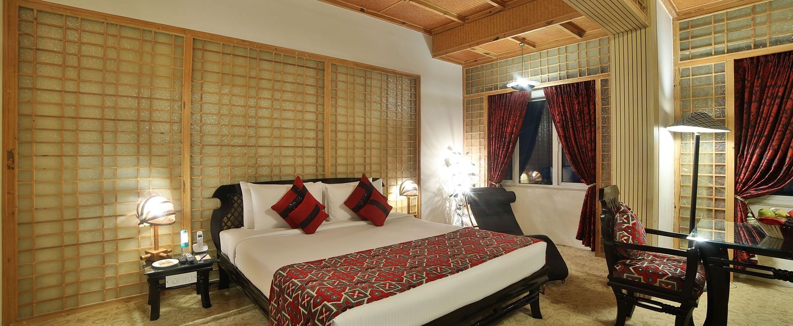 A luxurious hotel room with a richly patterned bedspread, elegant wooden furniture, and warm lighting A grand hotel suite with an opulent red and white decor, large bed, and seating area, reflecting a traditional style at Sitara Luxury Hotel in Hyderabad n