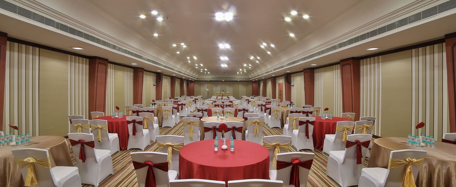  Seating arrangement in Terrace Hall A grand hotel suite with an opulent red and white decor, large bed, and seating area, reflecting a traditional style at Sitara Luxury Hotel in Hyderabad near Ramoji Film City.
