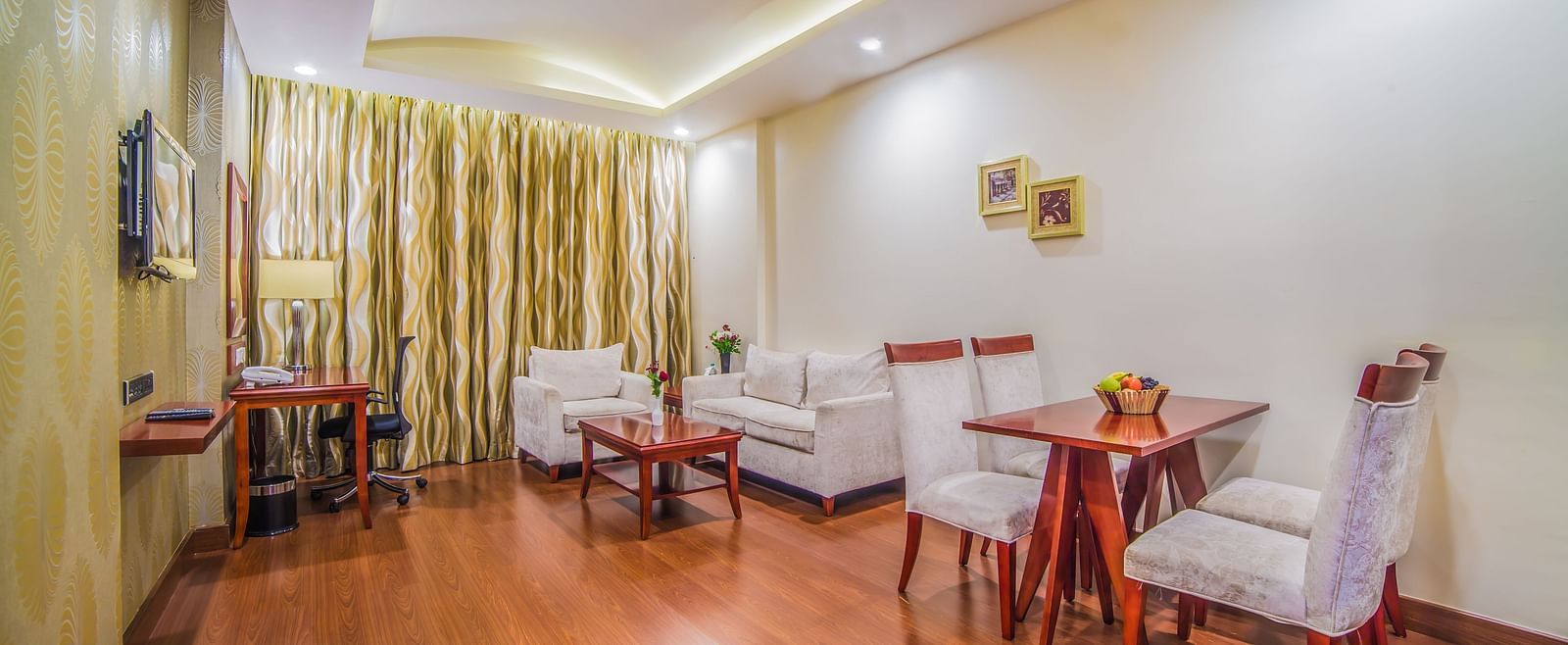 A bright and inviting hotel dining area with a wooden table set for two A grand hotel suite with an opulent red and white decor, large bed, and seating area, reflecting a traditional style at Sitara Luxury Hotel in Hyderabad near Ramoji Film City.