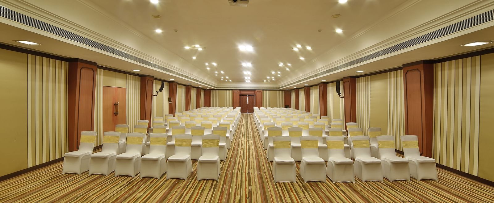  Seating arrangement in Terrace Hall A grand hotel suite with an opulent red and white decor, large bed, and seating area, reflecting a traditional style at Sitara Luxury Hotel in Hyderabad near Ramoji Film City.