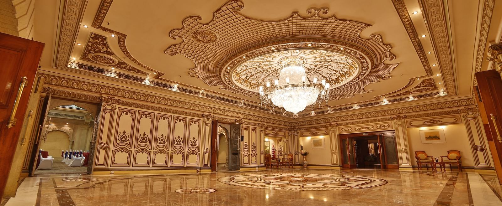  Interiors of Rang Mahal hall A grand hotel suite with an opulent red and white decor, large bed, and seating area, reflecting a traditional style at Sitara Luxury Hotel in Hyderabad near Ramoji Film City.