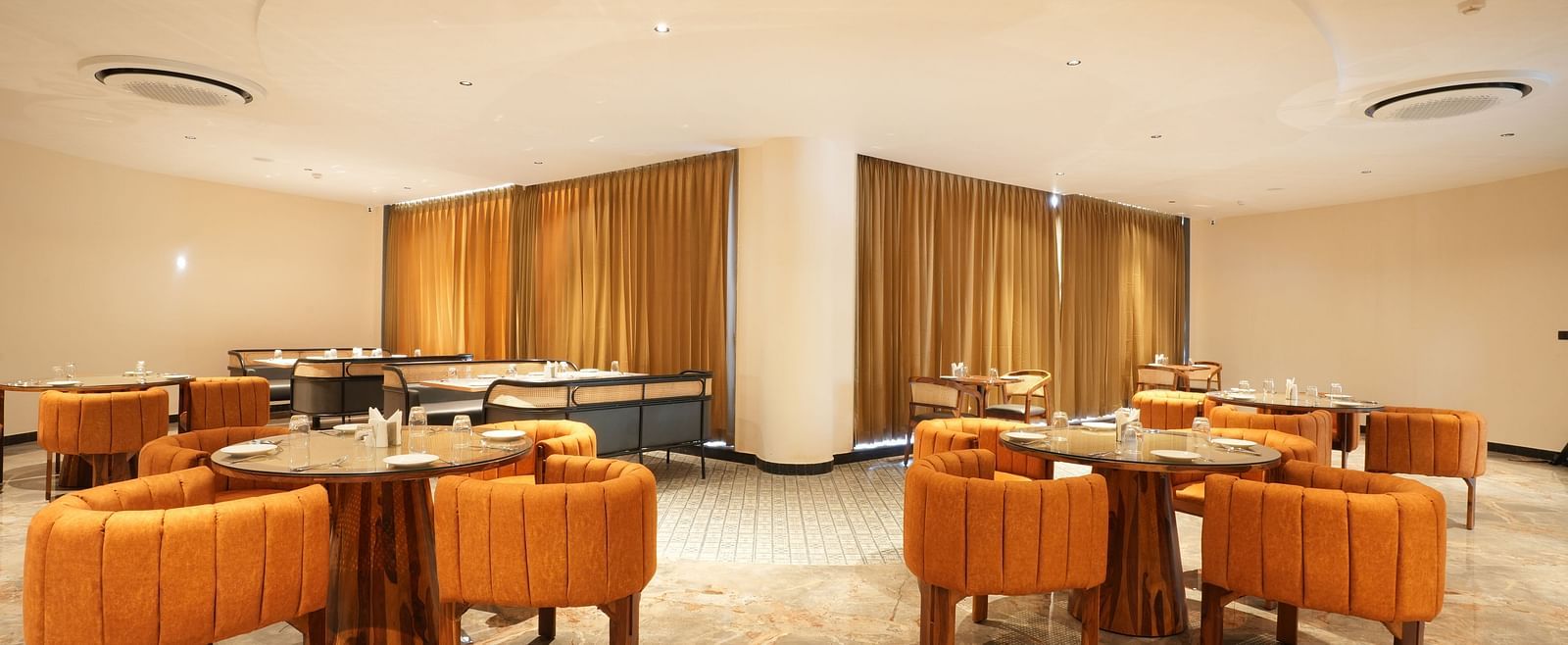 Fine Dine with multiple tables and orange chairs at The Qualia Resort Club & Brewery, Udaipur.