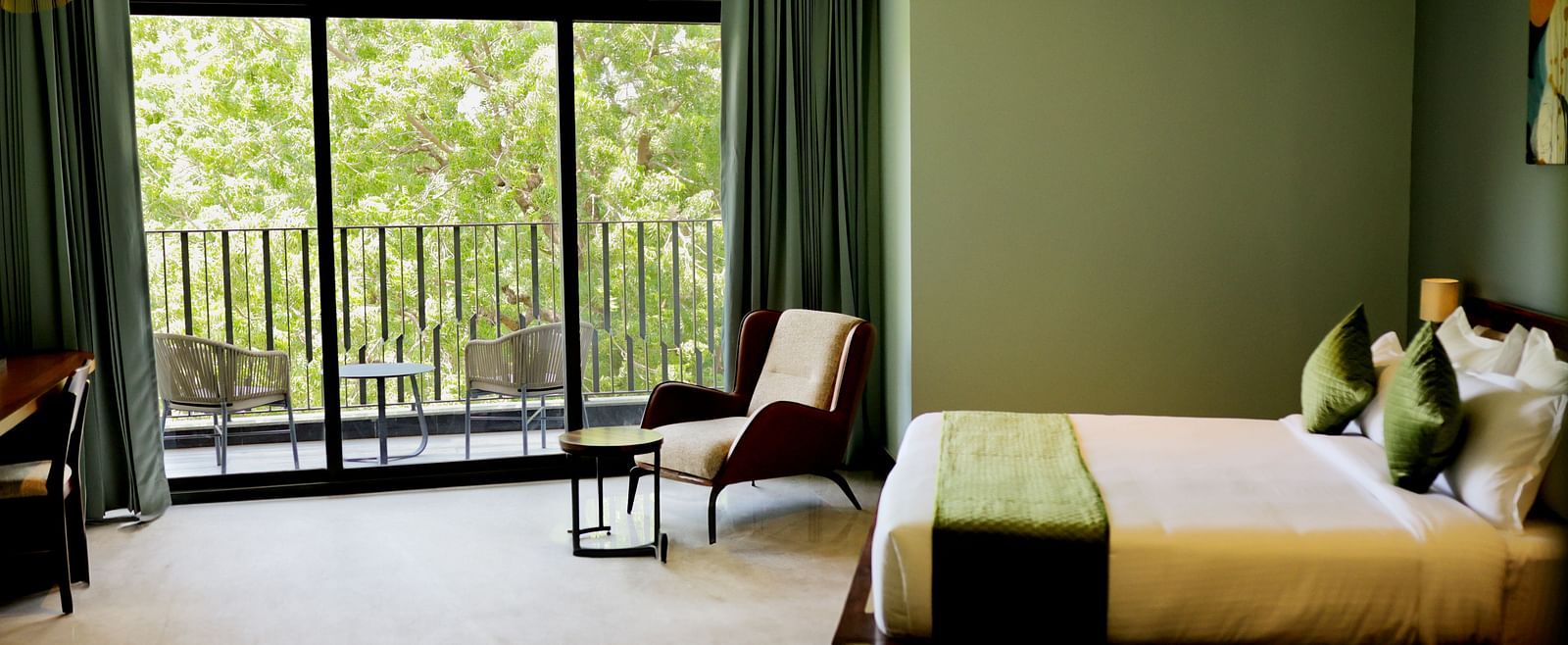 Club Suite with Valley View Sitout with a king size bed, a chair, and a balcony overlooking greenery.