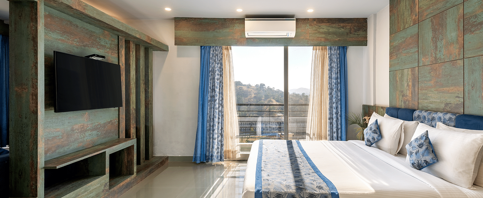 A bedroom with a neatly arranged bed and a tv mounted on the wall - Via Lakhela Resort & Spa