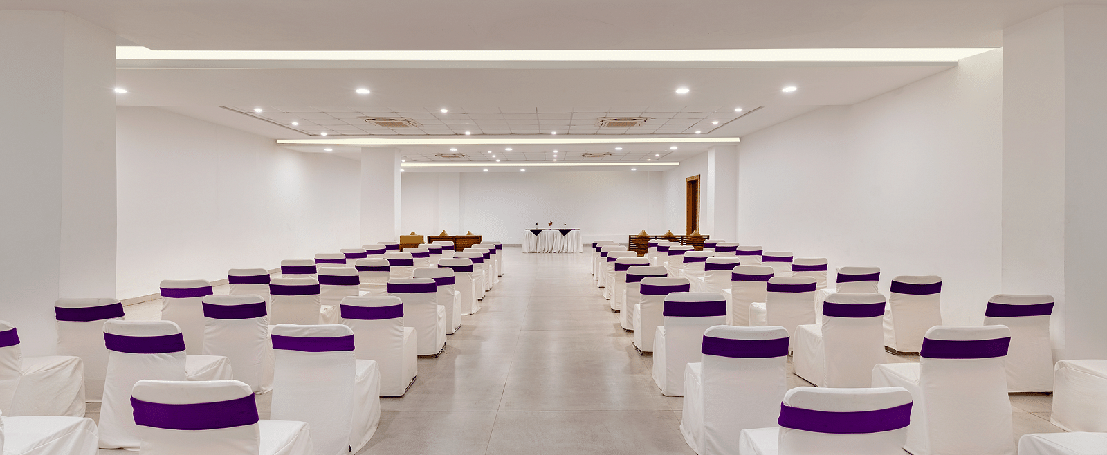 Empty conference room with rows of chairs draped with white tablecloths - Via Lakhela Resort & Spa