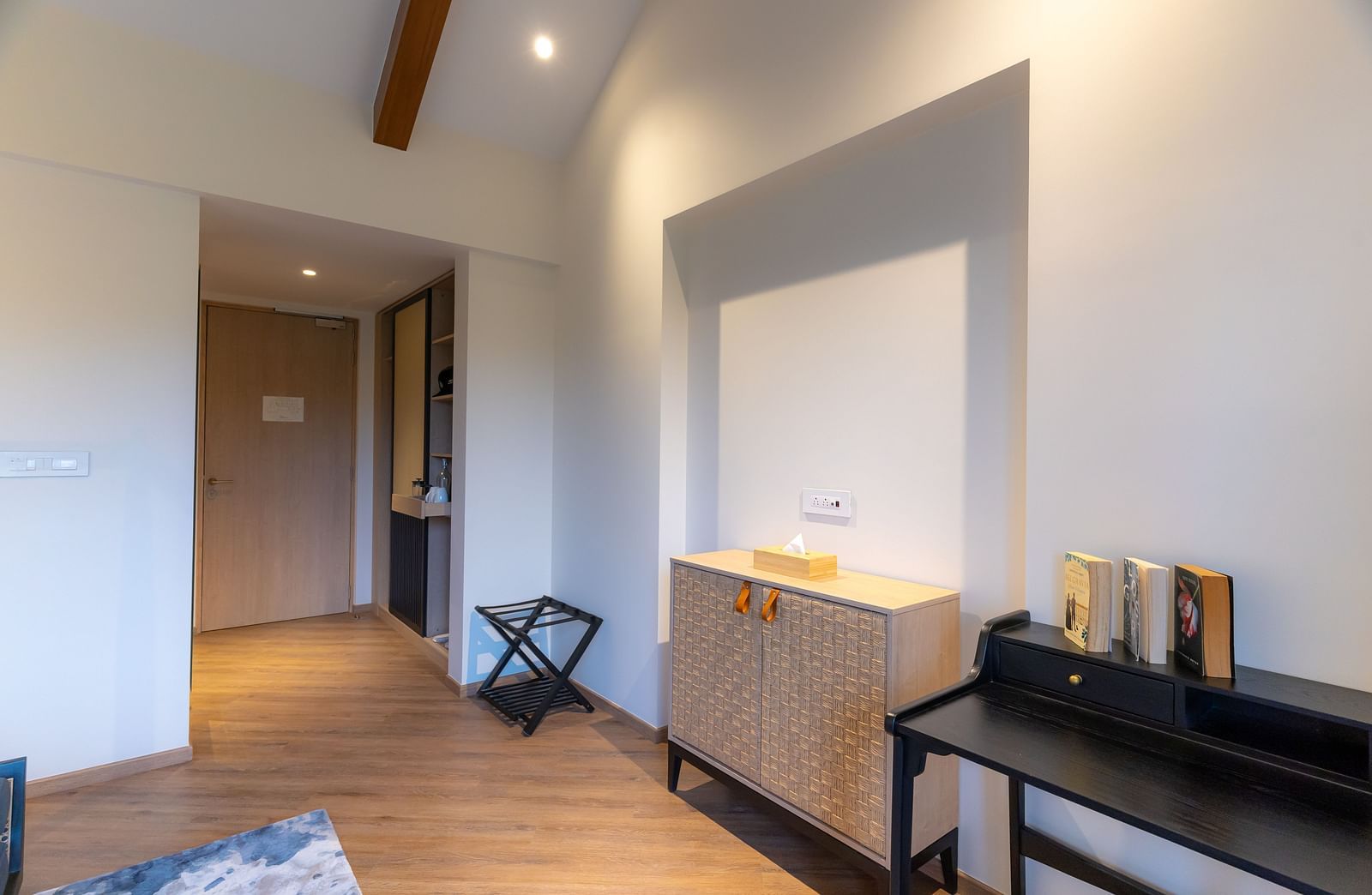 Hallway leading to a room with wooden storage area and table besides the wall at Nivasana Manali.
