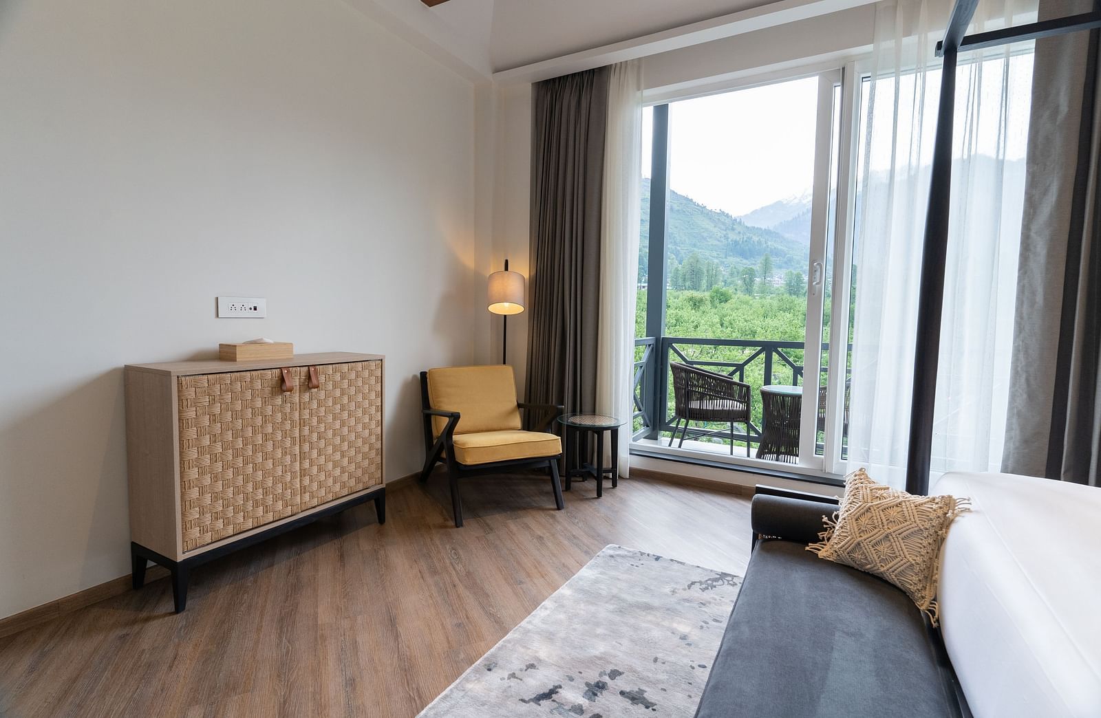 Cosy room with a bed, armchair, cabinet and a balcony view at Nivasana Manali.