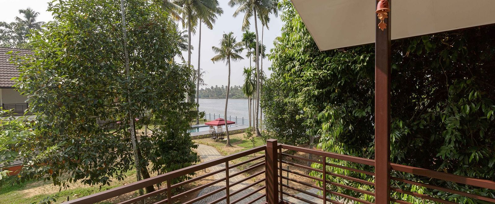 A balcony with a railing overlooking a body of water and palm trees.