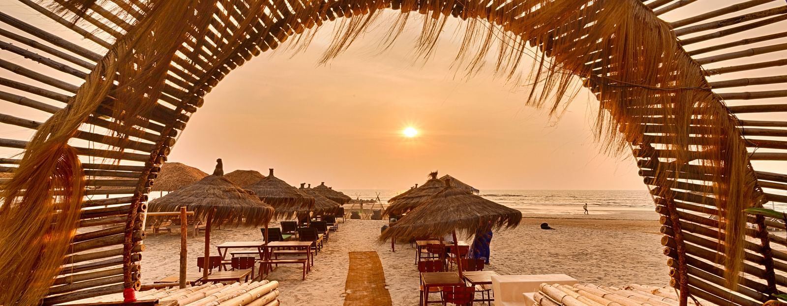 Entrance view framed with palm arch and sunset backdrop at Royale Amata by the Beach Restaurant