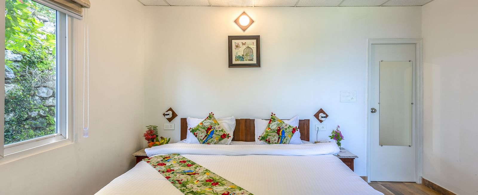 a double bed with a bed runner and pillows on it inside one of the rooms - neer ganga resorts