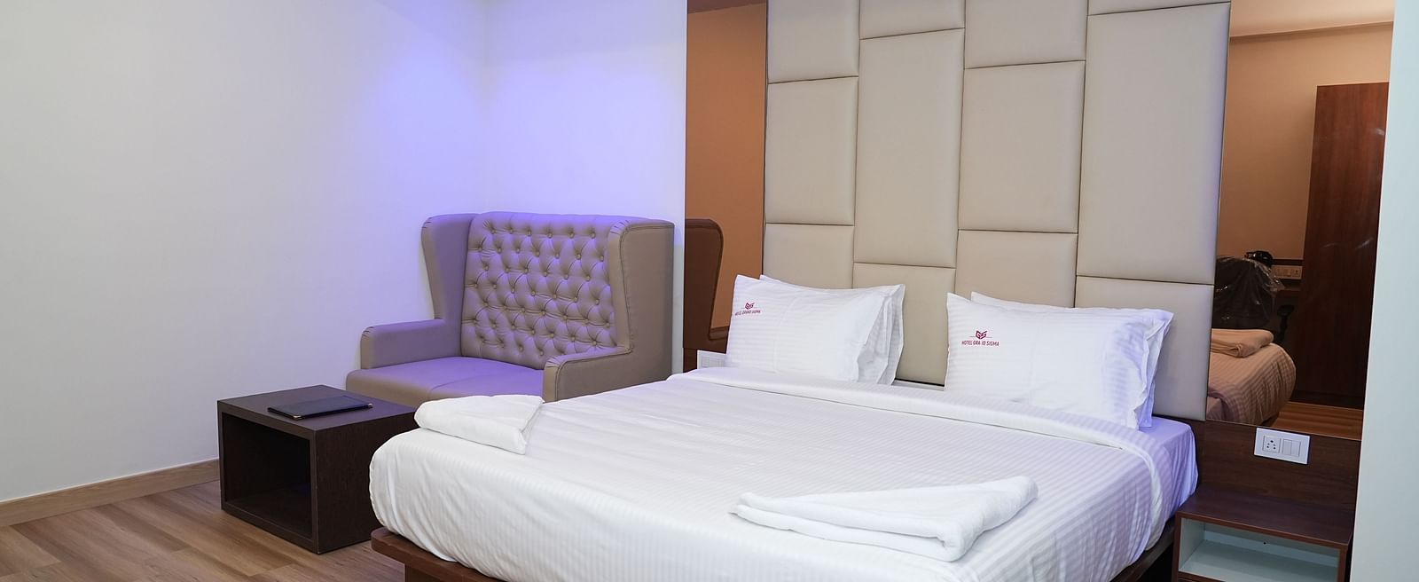 corner view image of the suite with a comfortable double bed along with a cushioned couch at the far end of the room - Hotel Grand Sigma