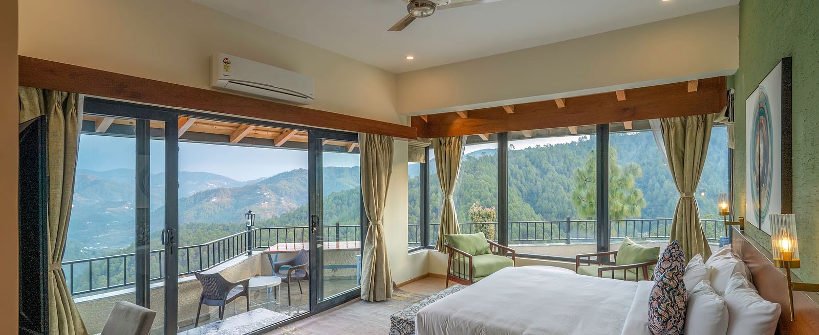 Spacious room with a large bed and a large glass sliding door leading to a balcony with a mountain view at The Chamomile Estate.