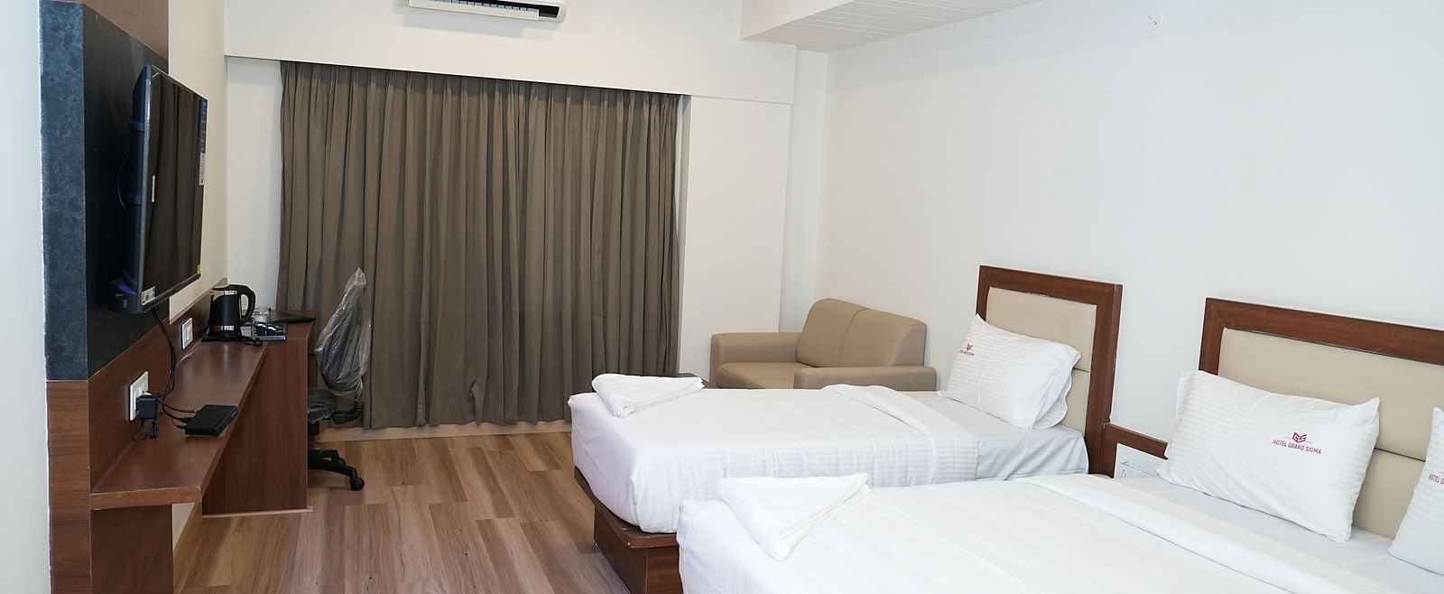a room featuring a double bed along with a single bed along with huge windows with curtains drawn over it - Hotel Grand Sigma