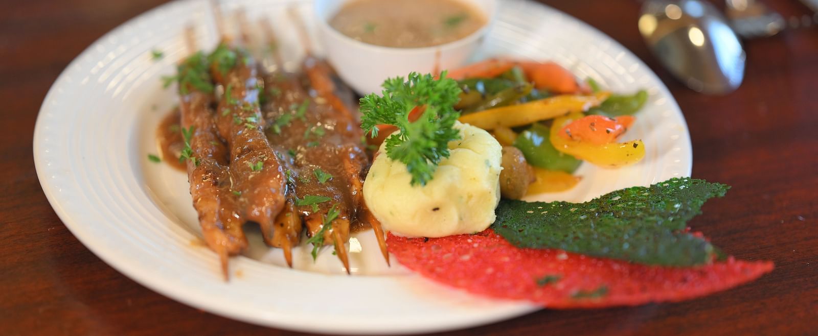 Grilled skewers with a side of mashed potatoes, mixed vegetables, and sauce at Royal Comfort Regency.