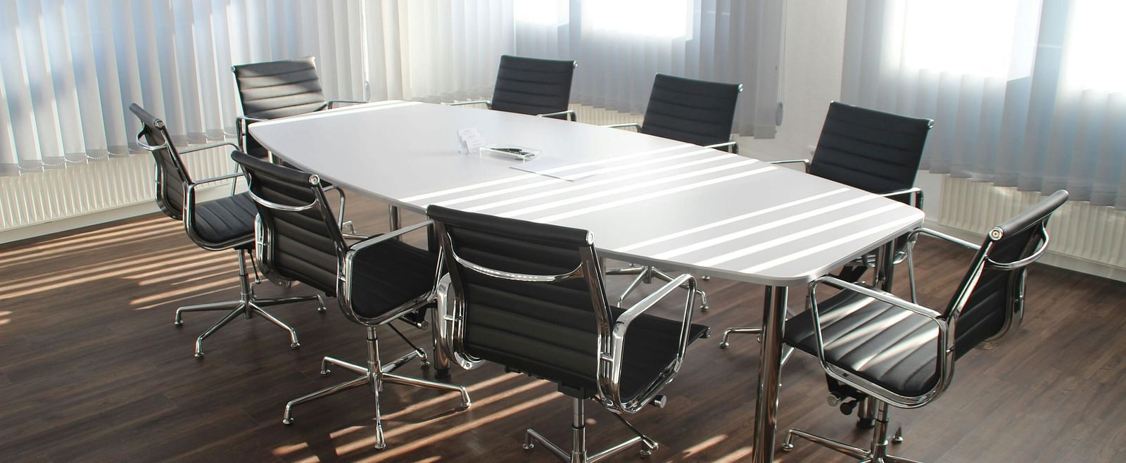 A boardroom with a large table and chairs arranged around it.