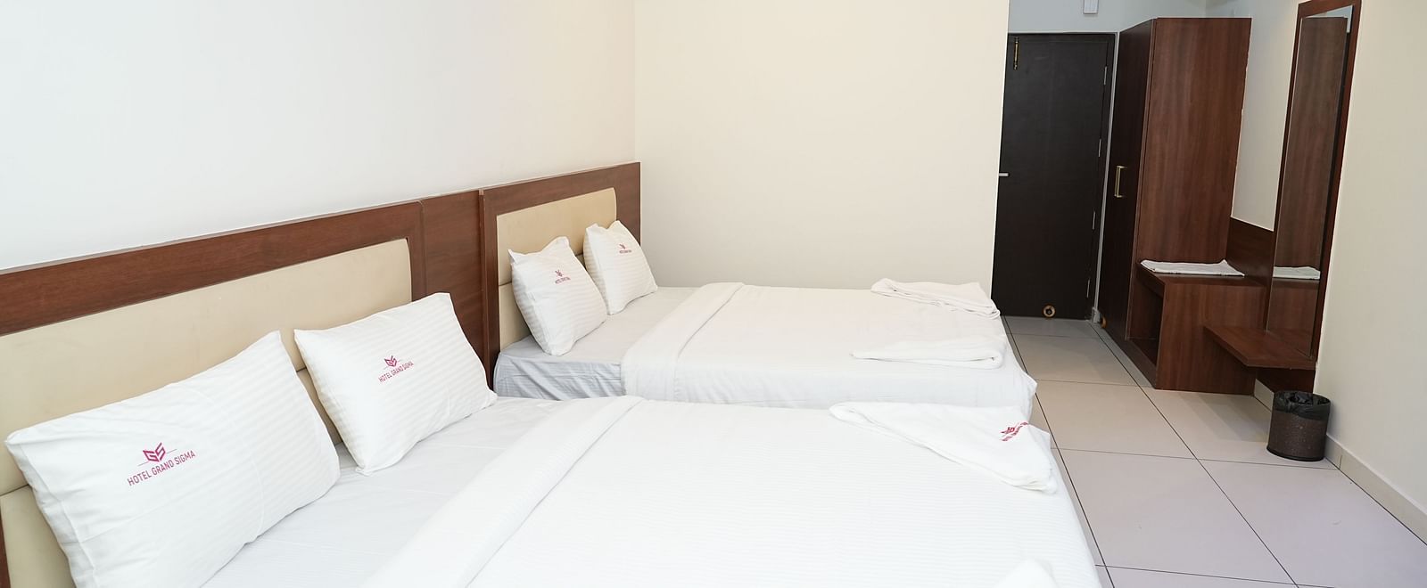corner view of the double beds at hotel grand sigma with the entrance corridor featuring at the end of the room - Hotel Grand Sigma