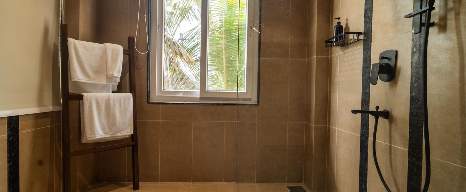 Spacious walk-in shower with large window, wooden towel stand, and sleek design at Kssemya.