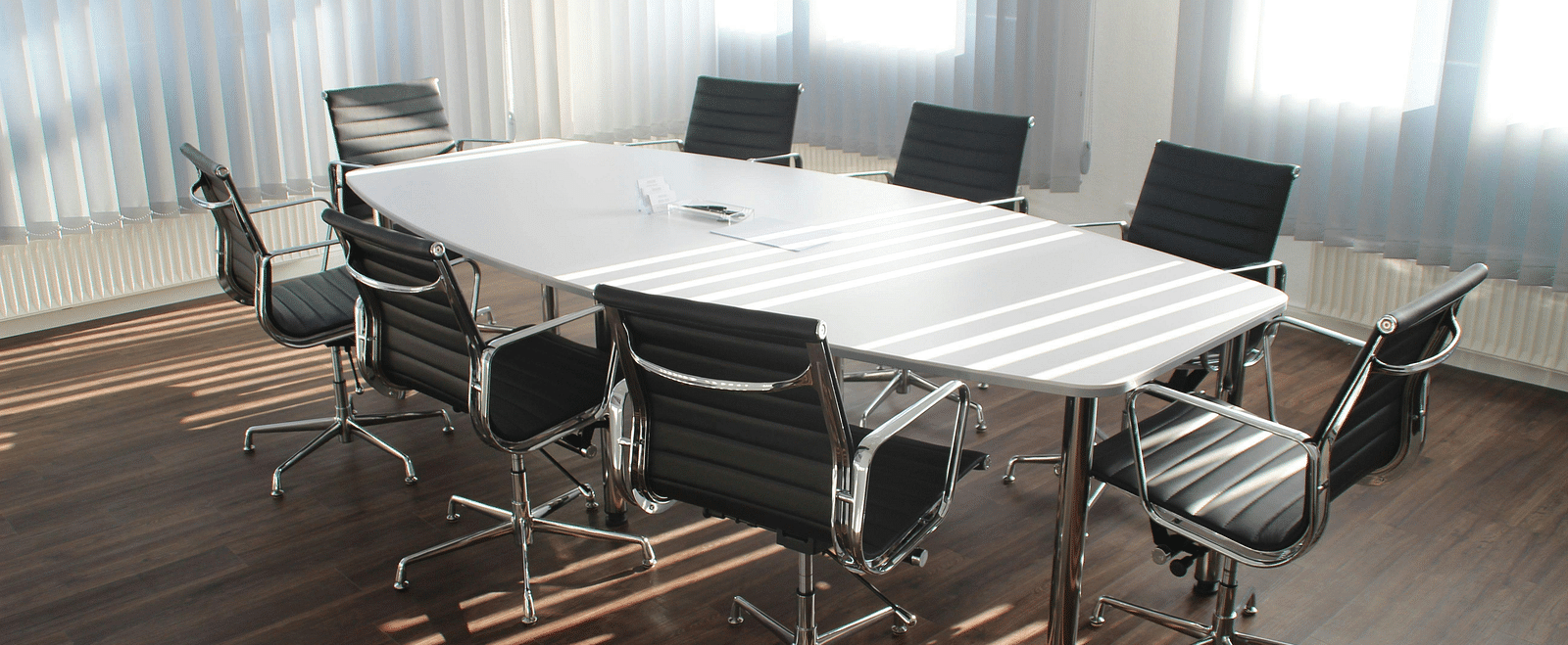 A boardroom with a large table and chairs arranged around it.