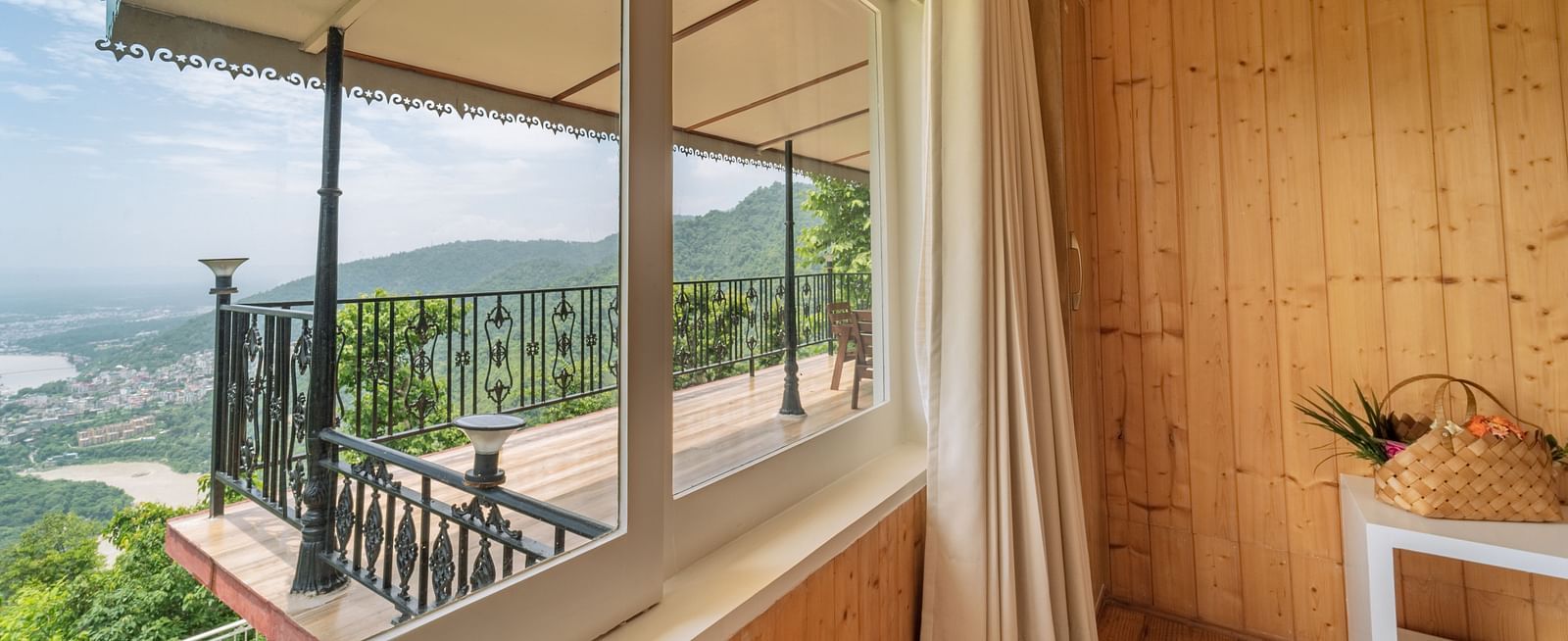 a view from the window of a balcony and the valley behind it inside one of the rooms - neer ganga Resorts