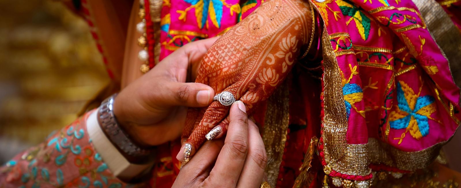 An image of a man putting a ring on his to be wife hand in a wedding ceremony