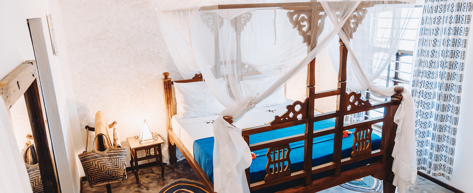 View of a bed, bed side table, ceiling fan and air-conditioner in the background - Shooting Star Boutique Hotel.