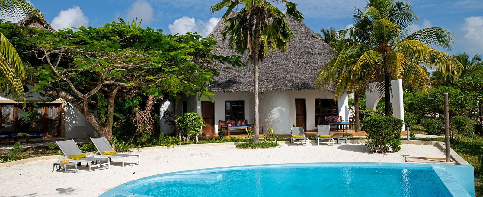 View of a swimming pool with trees and shooting star boutique hotel in the background.