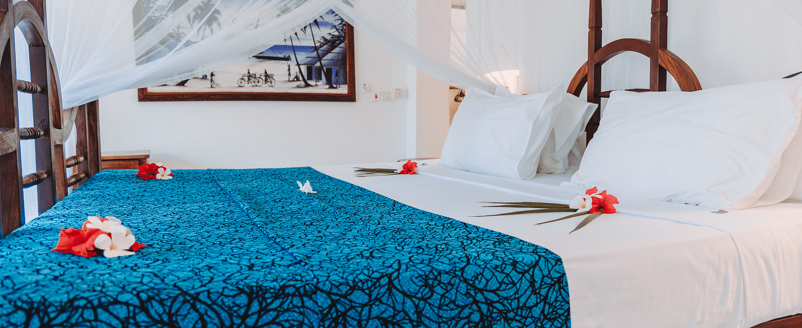 Side view of a bed with mosquito net and a framed image can be seen on the wall in the background - Shooting Star Boutique Hotel.