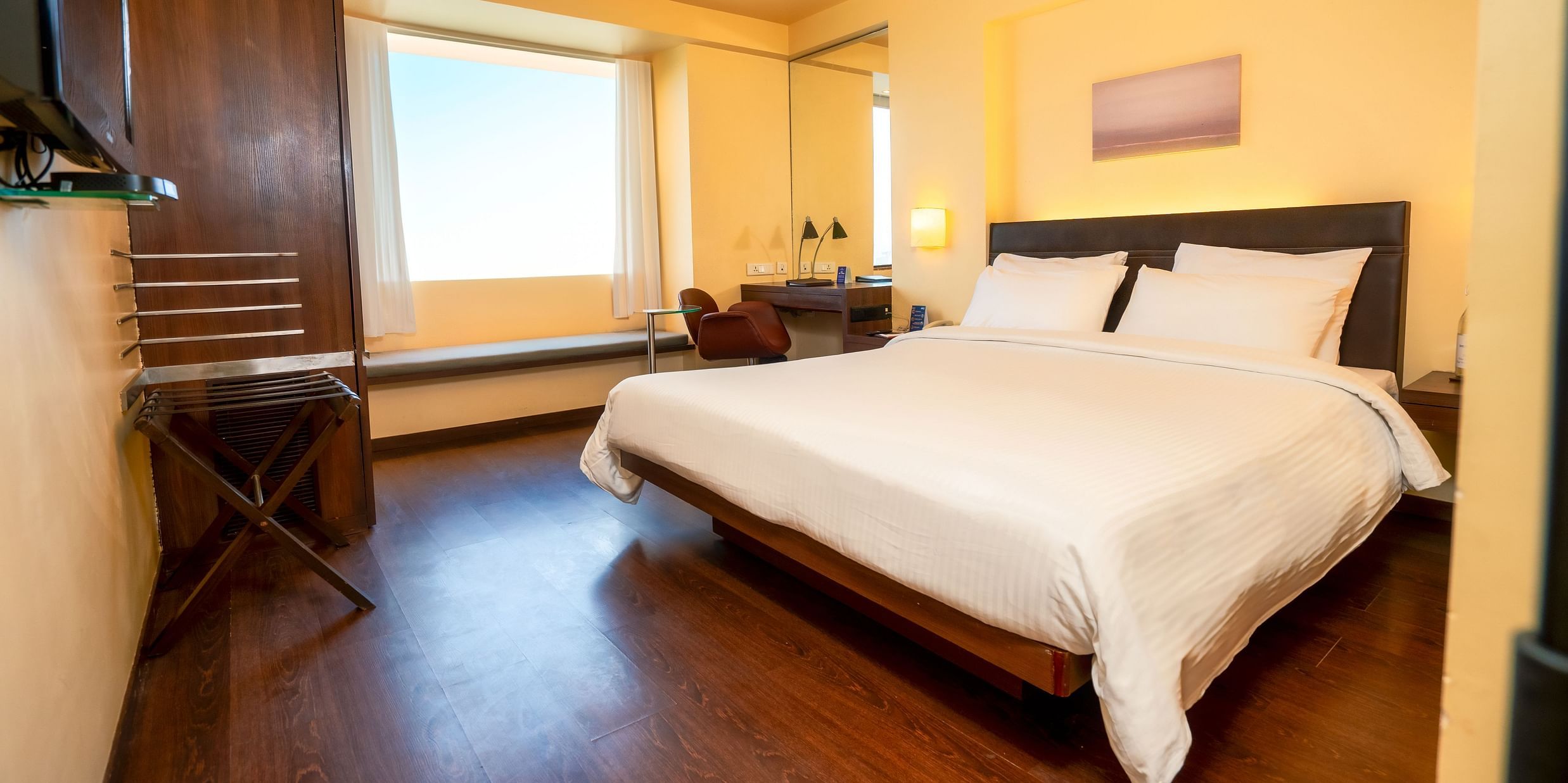 A side view of the executive room with plushy king size bed, a window with a view at Marasa Sarovar Portico, Rajkot