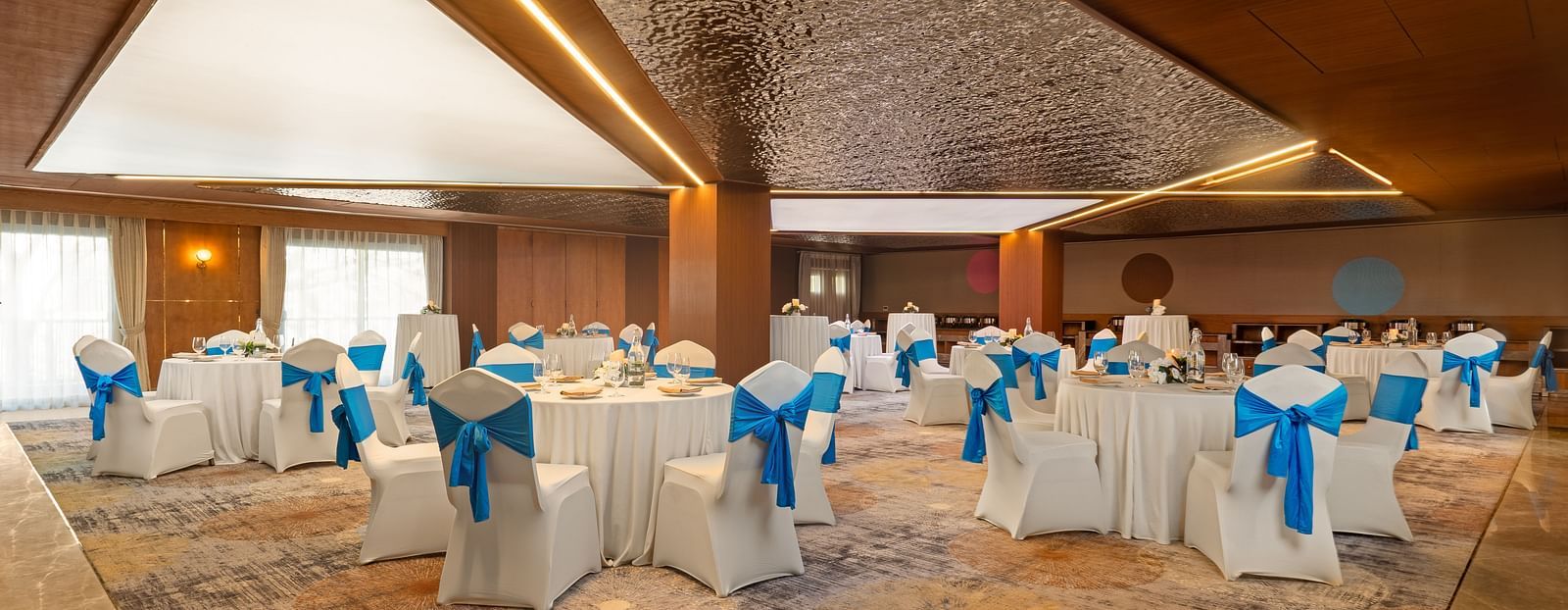 Indoor wedding ceremony with blue-clad performers, high ceilings, and warm lighting, capturing a cultural ritual in progress.
