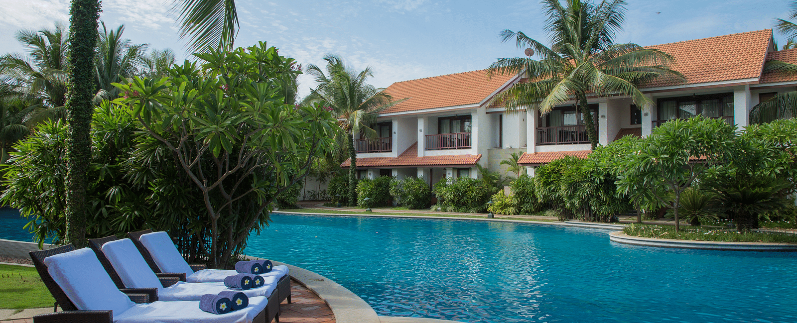 Luxury resort with a swimming pool, lounge chairs, and tropical greenery at GRT Hotels.