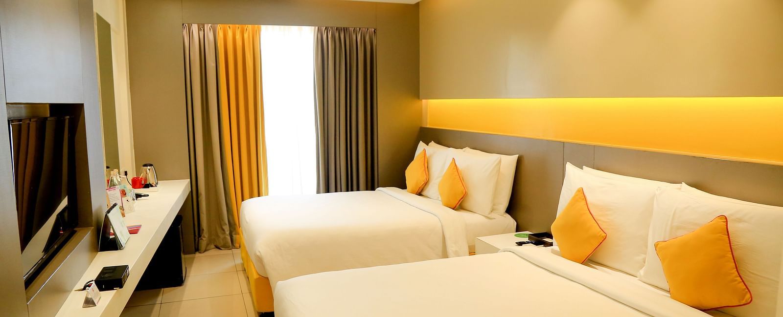  Spacious twin beds with headboards line the wall, large windows with curtains cover them
