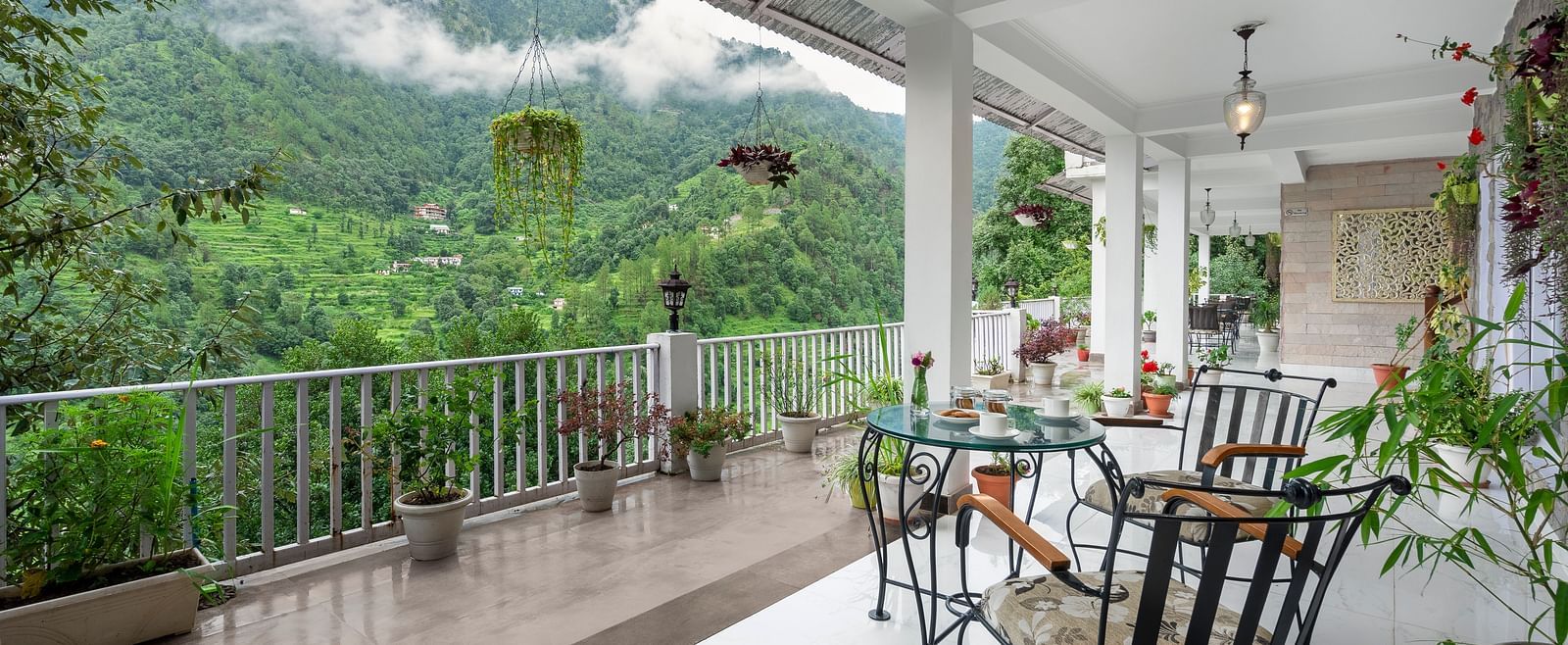 Open-air veranda with seating and potted plants overlooking forested hills, at BluSalzz Collection - Suvaasa Resort, Ramgarh.