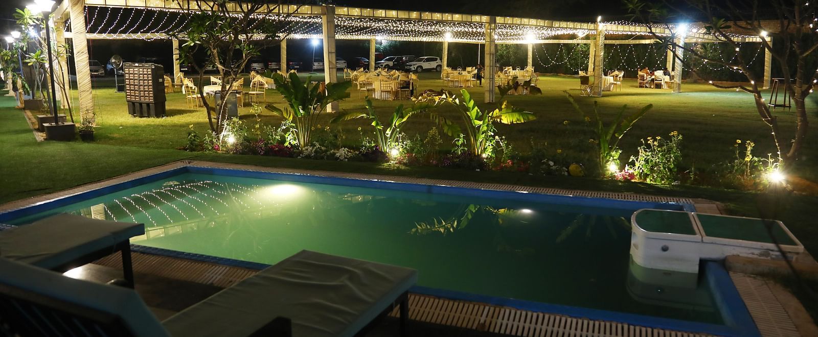 Poolside view illuminated with lights during nighttime at Tisya Farms, Gurgaon.