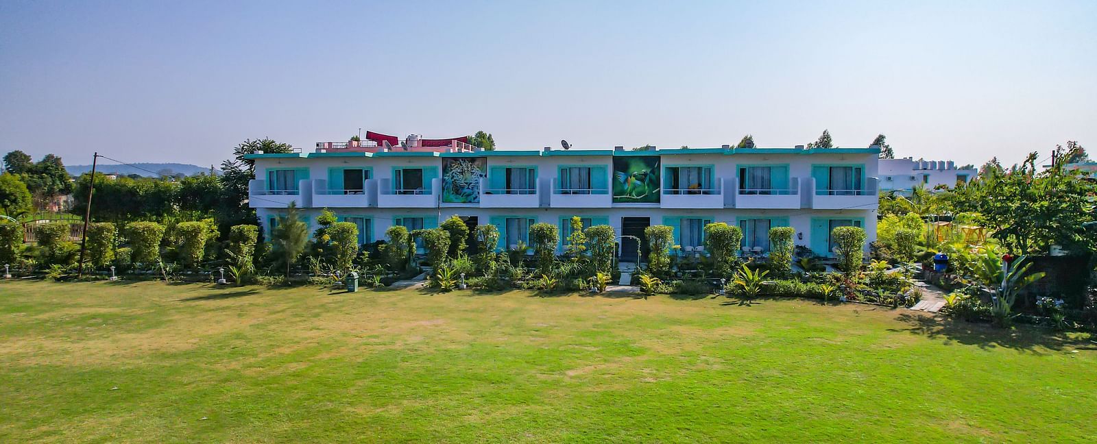 Open lawn at Vedikant Resorts The Mallard Corbett with trimmed grass, resort buildings in the background, and no visible guests.