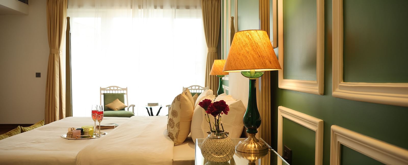A room at Dileep Kothi, Jaipur with a double bed, side tables and a large window