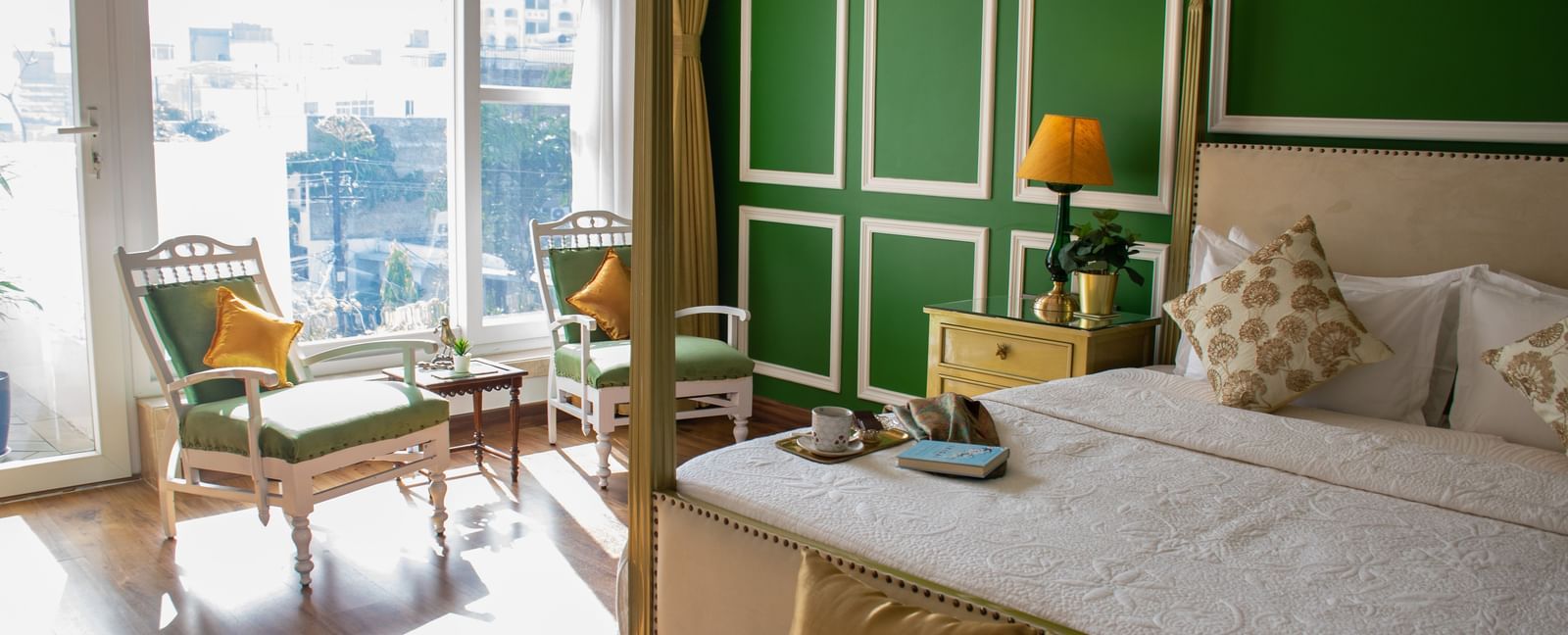 A room at Dileep Kothi, Jaipur with a double bed and a coffee table arrangement placed in front of a sliding door