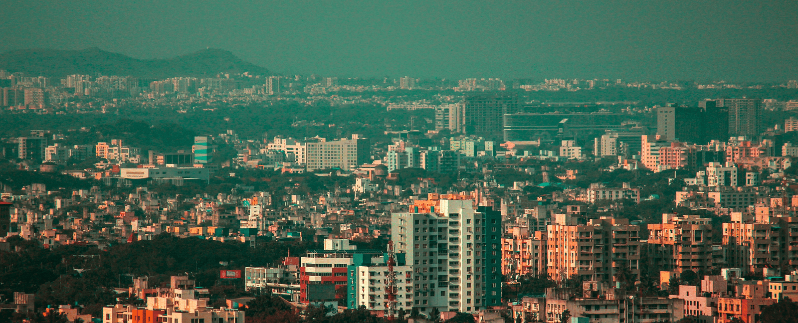 An overview of the city of Pune with high rise and small buildings in view in daylight.