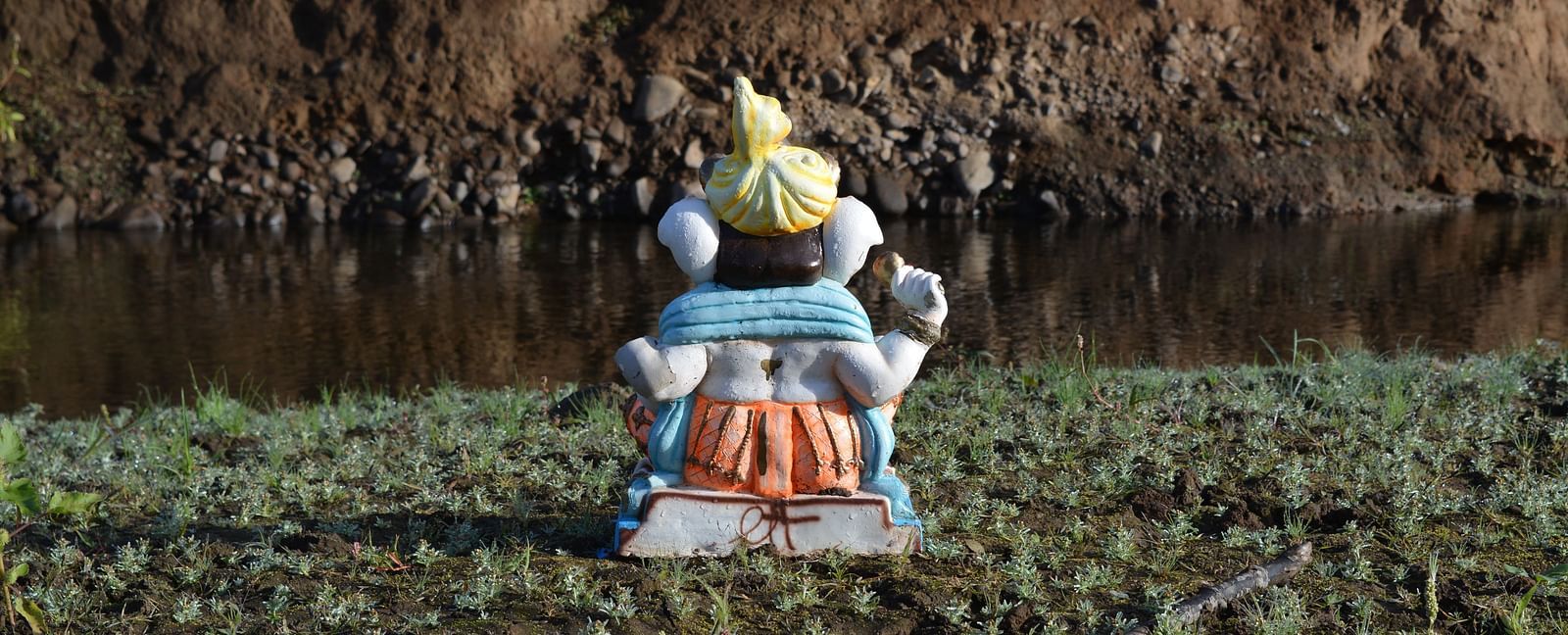 An overview of the hindu deity Ganesh's Idol in front of a waterbody.