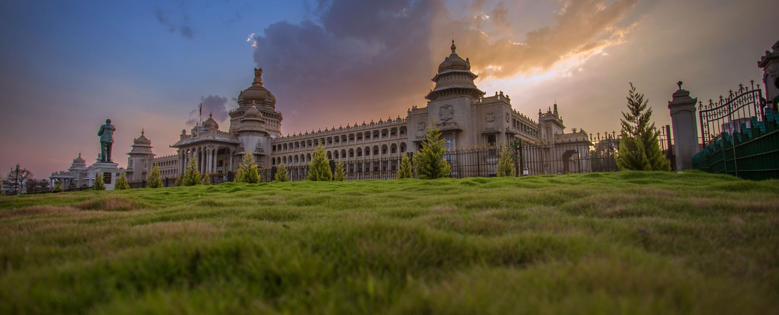 Vidhan Soudha building in Bangalore, Karnataka, with detailed stone architecture, green lawn and cloudy sky.