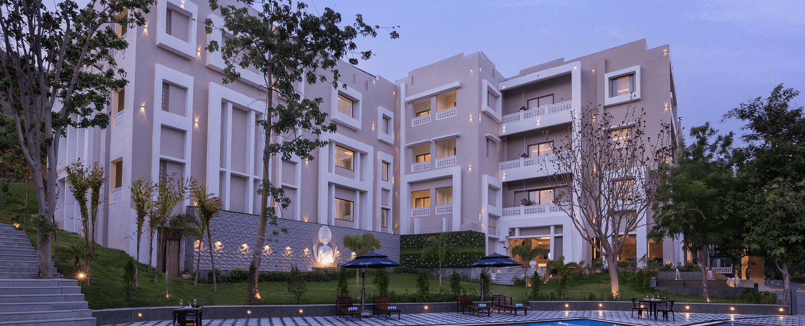 An overview of the Swimming pool with the facade of Essentia Luxury Resort & Spa, Udaipur in view.