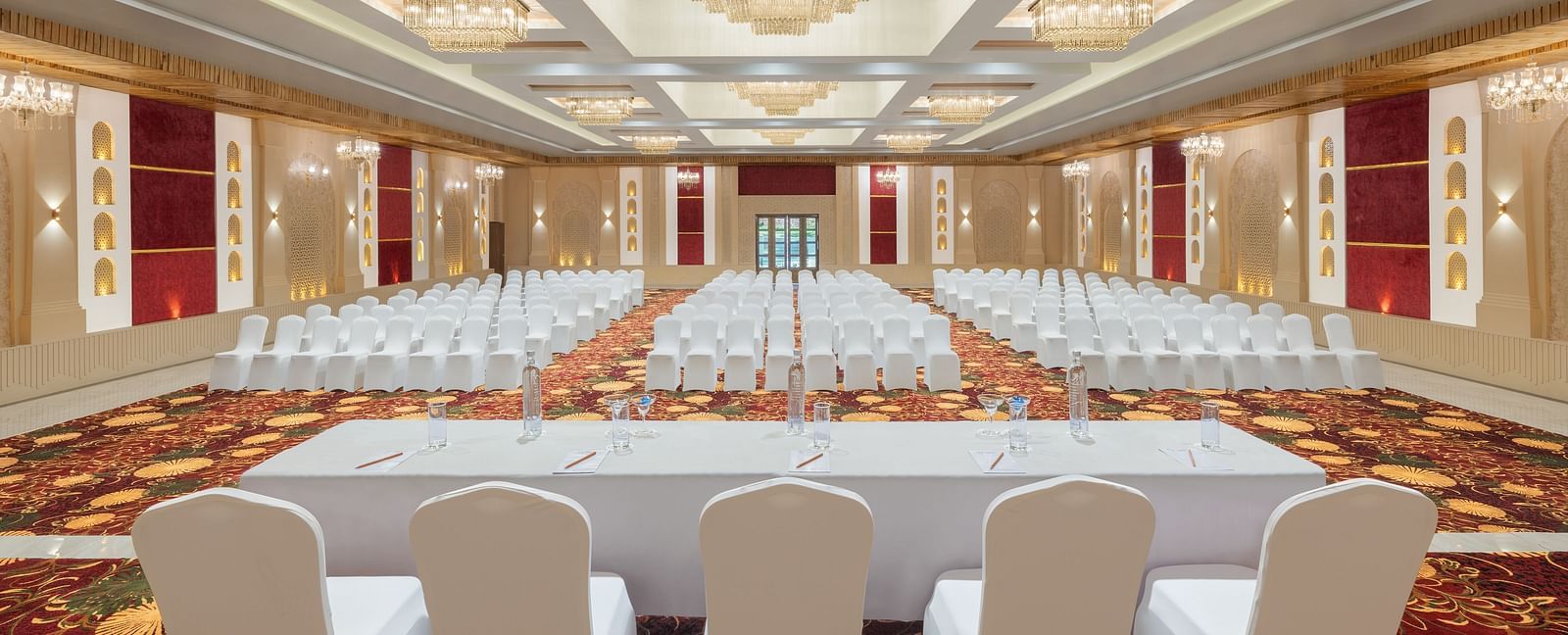 Grand Ballroom banquet with chair setting facing towards the stage with a group of chairs placed in front of a single table at A dining setting of Blue Salt and Coffee at Essentia Luxury Resort & Spa, Udaipur.. 