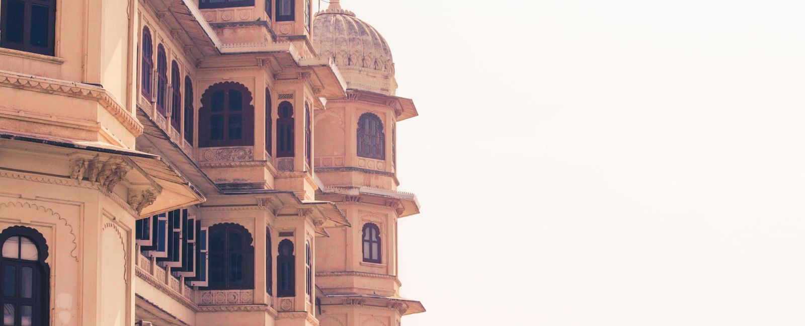 Close-up of a intricately designed windows and balconies of a palace under a clear sky.