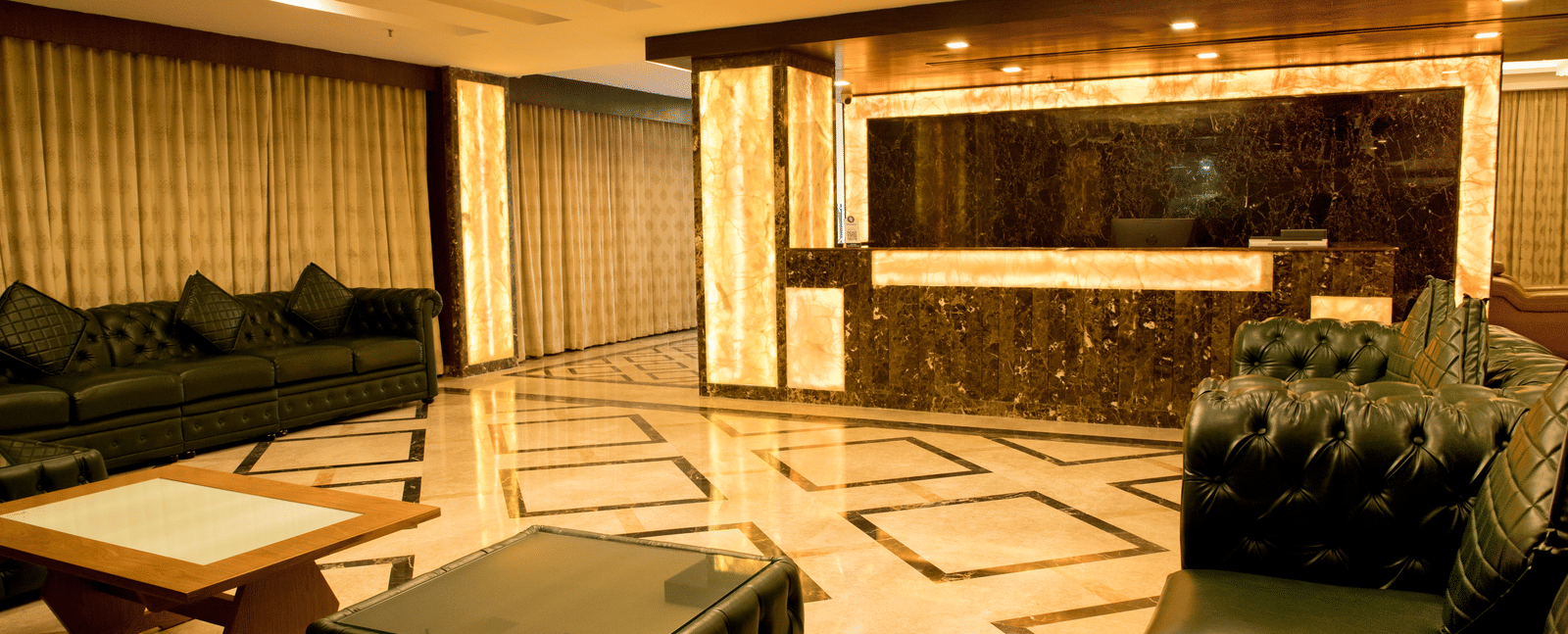 A hotel lobby at Benzz Park Chennai with comfortable seating areas, stylish decor, and ornate flooring.