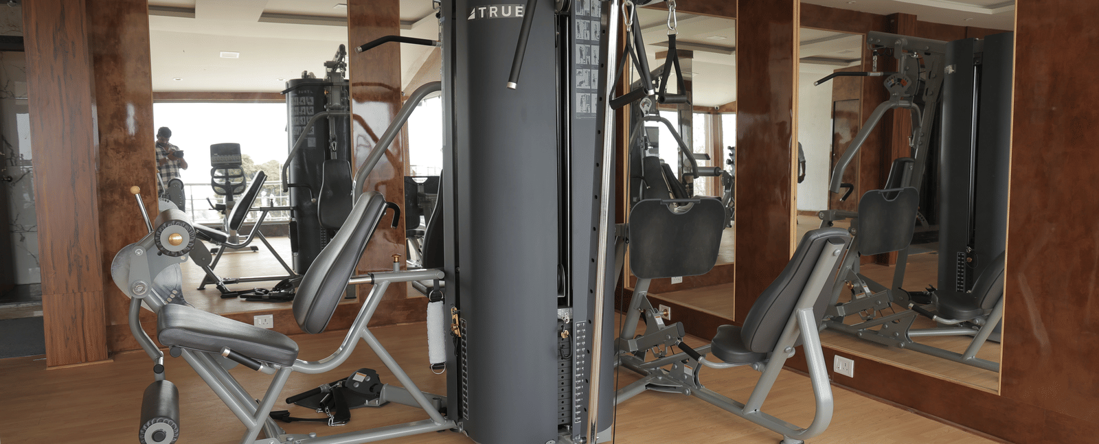 A well-equipped gym with various exercise machines and mirrored walls - Benzz Park, Kodaikanal