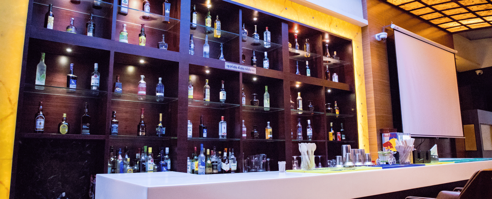 Side view of the bar featuring the bar counter and a display cabinet stacked with various liquor bottles on display at Benzz Park, Vellore.