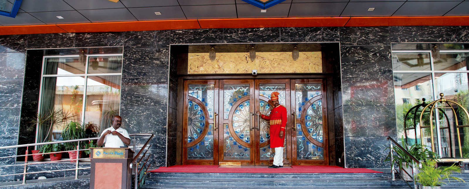 Entrance of Benzz Park, Vellore, featuring a doorman wearing a red coat ready to open the door for the guest.