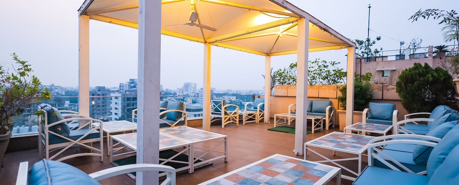 An outdoor dining setup at Hotel Ashok Nagpur featuring cushioned chairs and tables arranged on a rooftop or terrace during the evening.