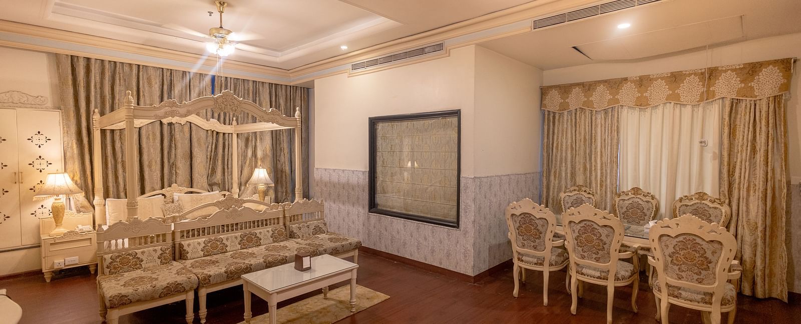 King Suite eaturing a seating area with a sofa and coffee table, a dining area with four chairs, and neutral-toned decor.- Hotel Ashok Nagpur